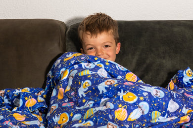 jongen onder verzwaringsdeken op bank