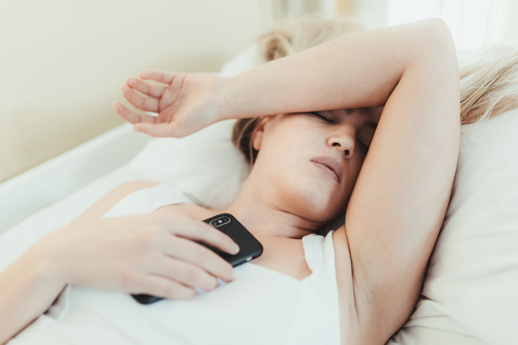 vrouw ligt met telefoon op bed