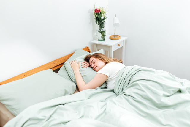 Femme dormant avec une couverture lestée Novaline à housse en coton vert